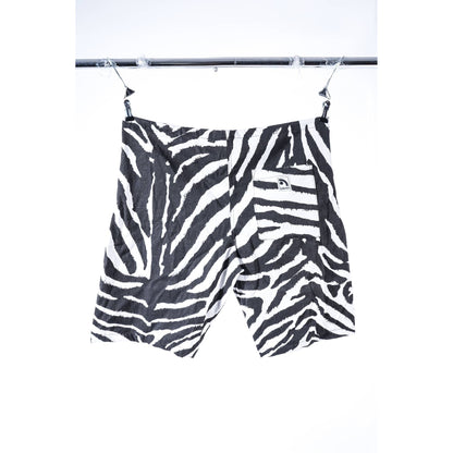 Black and white zebra print baggy skate shorts hanging from a metal clothesline against a white background.