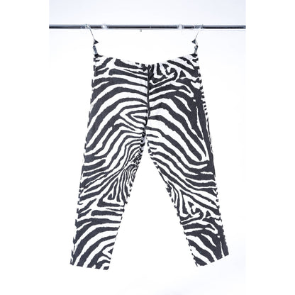 Black and white zebra print cropped baggy skate pants hanging from clips on a metal rail against a white background.