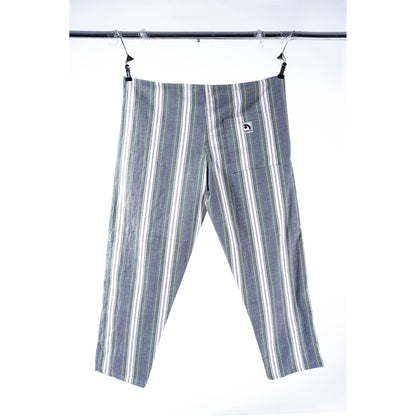 A pair of striped cropped pants in gray, white, and green, hanging from a black metal clothesline against a white background. A small white brand patch is visible on the back pocket.