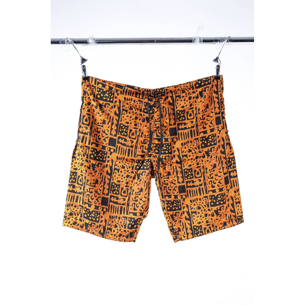 Orange and black patterned Limpies baggy skate shorts hanging from a black clothesline against a white background.