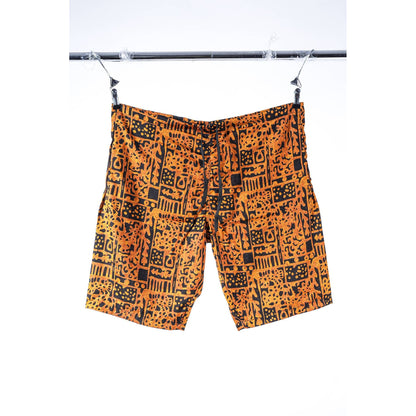 Orange and black patterned Limpies baggy skate shorts hanging from a black clothesline against a white background.