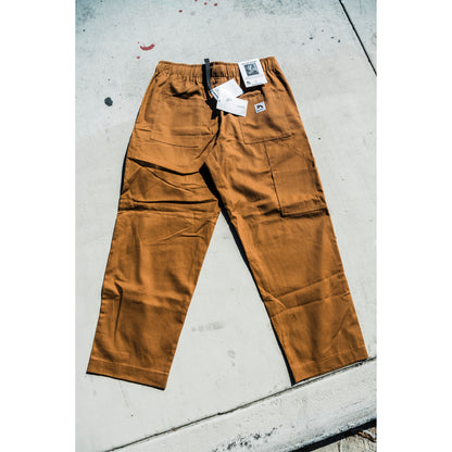 Brown baggy skate pants with tags on a concrete surface