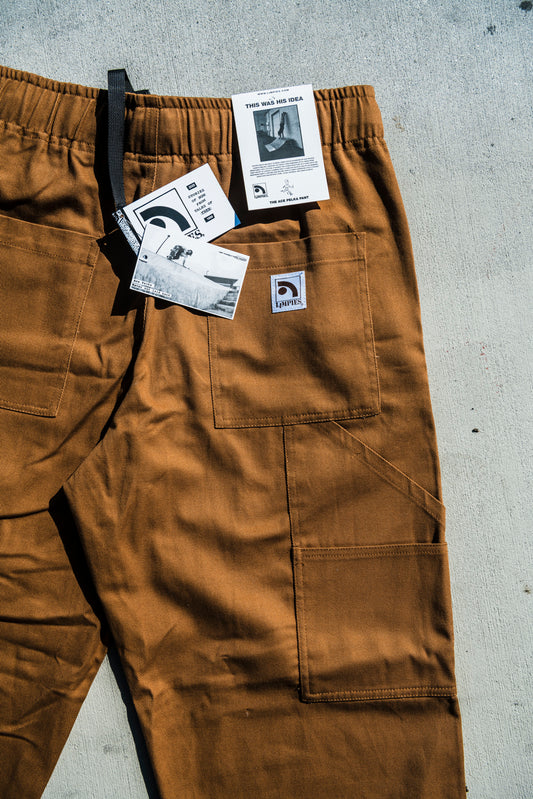 Brown baggy skate pants with tags on a gray concrete surface