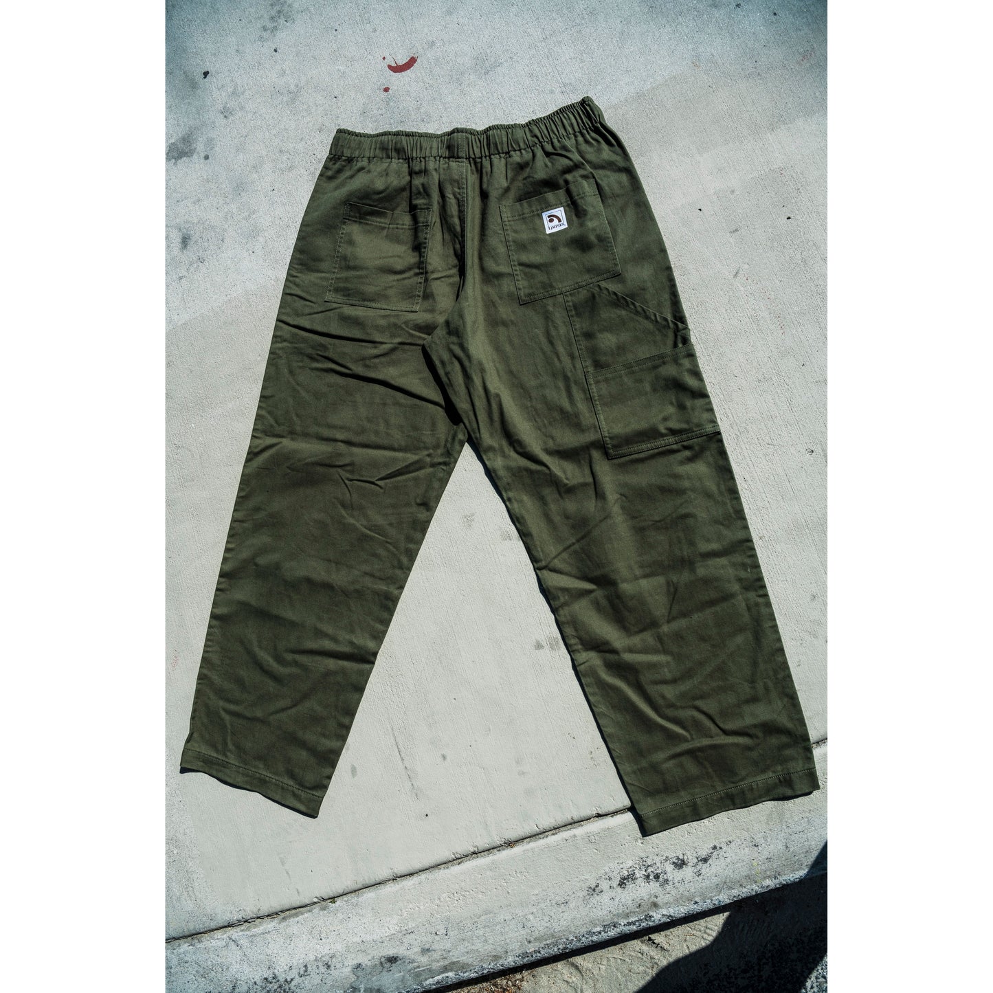 olive green baggy skate pants on a concrete surface