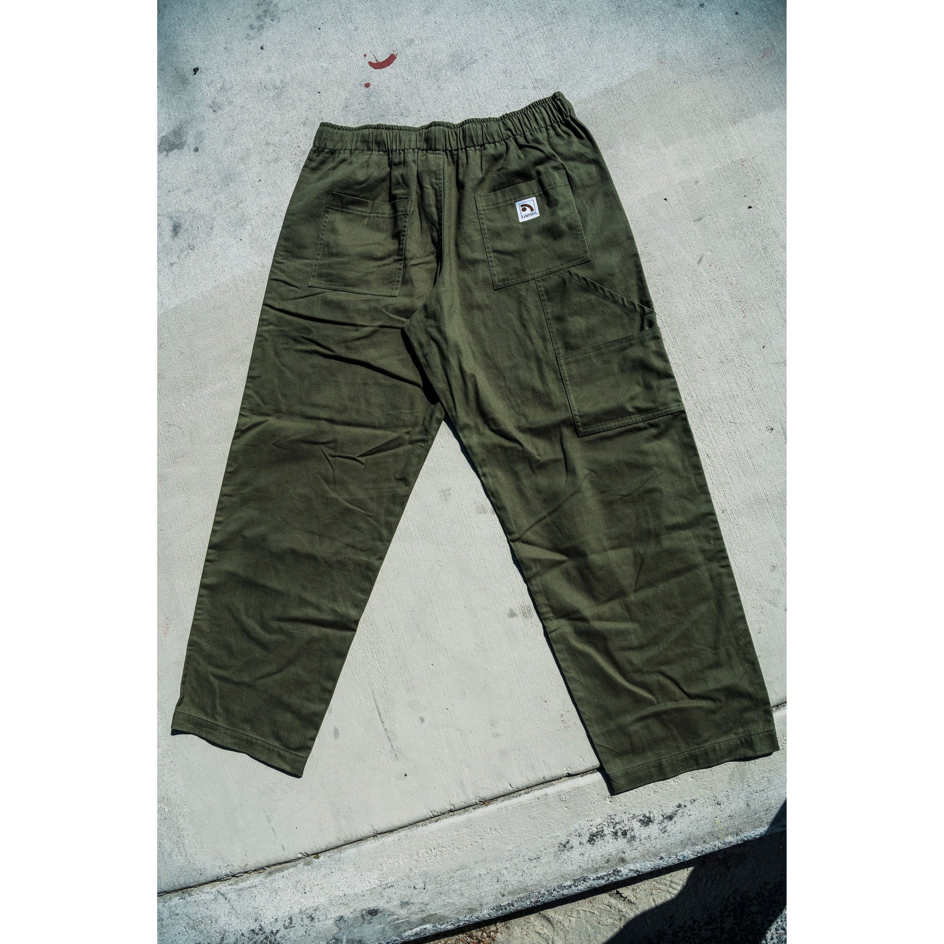 olive green baggy skate pants on a concrete surface