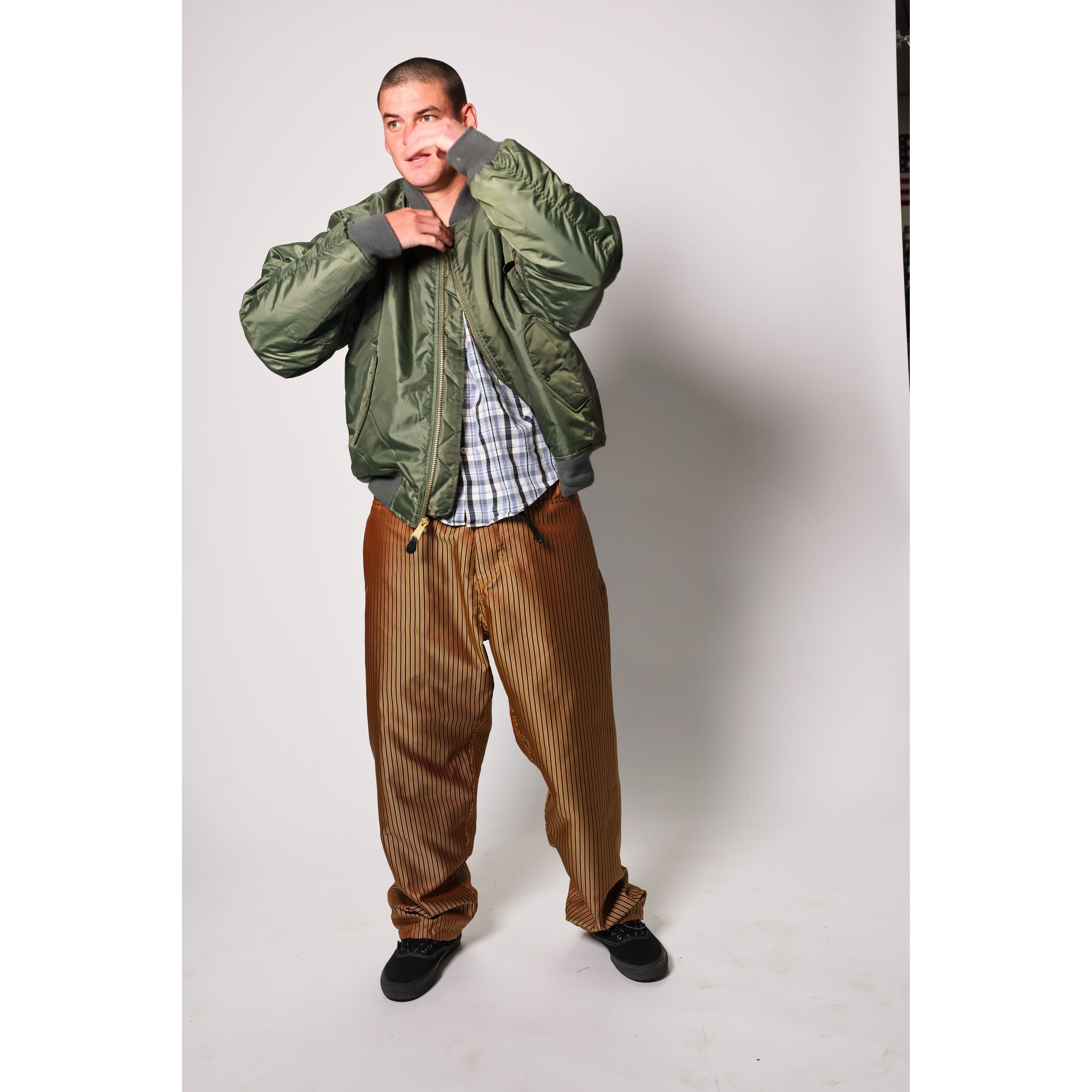 Baggy skate pants in burgundy with a gold stripe. These retro striped skate pants offer a bold 90s street style and a perfect baggy fit for the streets. Made in USA.