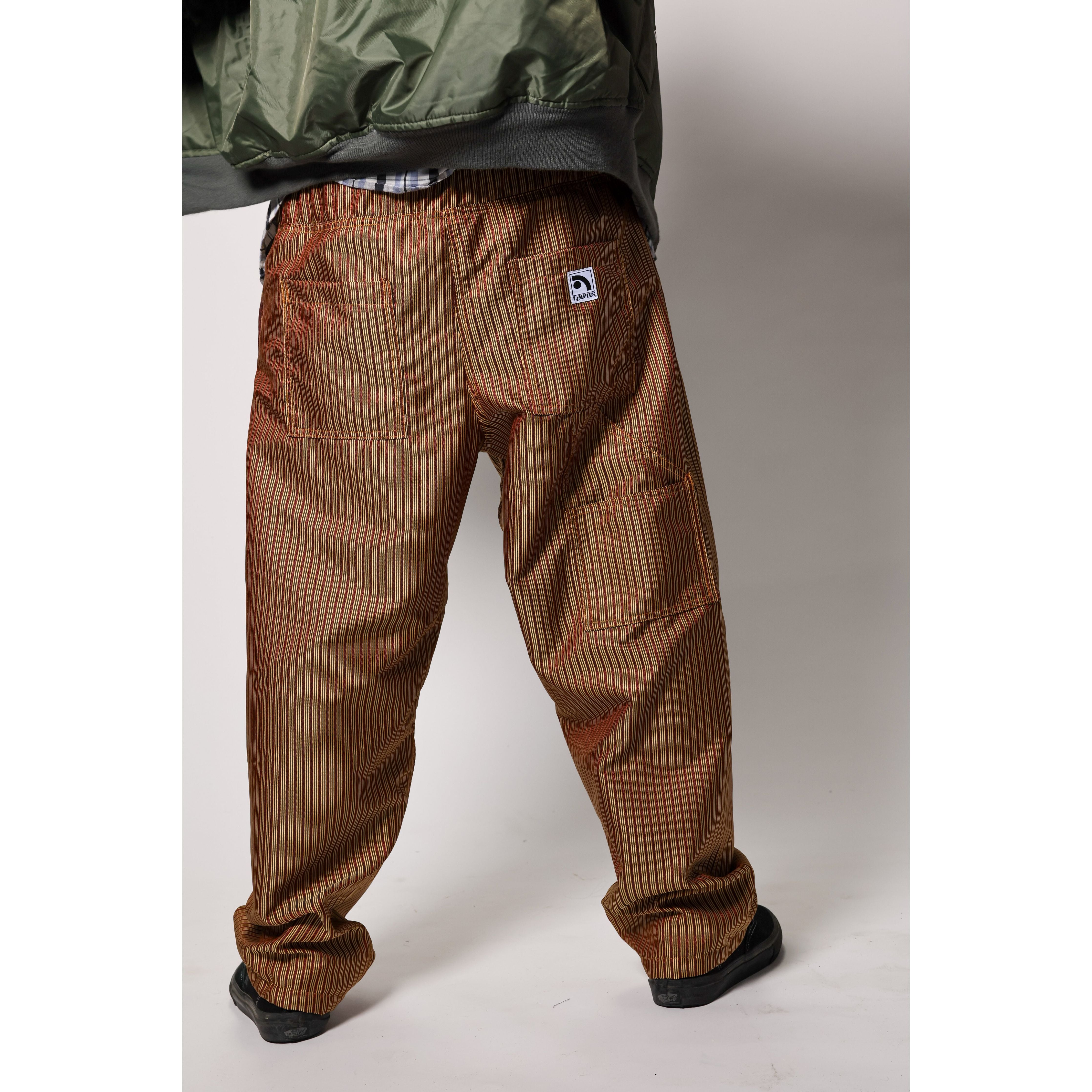 Baggy skate pants in burgundy with a gold stripe. These retro striped skate pants offer a bold 90s street style and a perfect baggy fit for the streets. Made in USA.