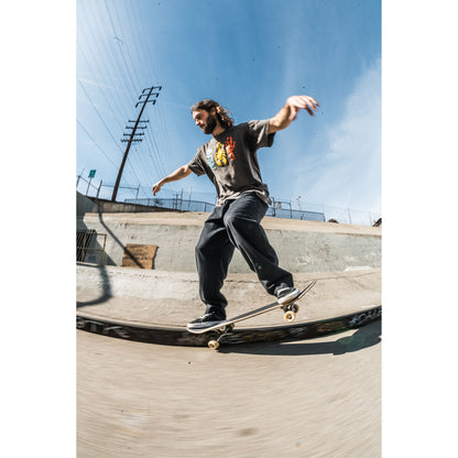 Person skateboarding in baggy skate pants on a concrete ledge with a clear blue sky in the background