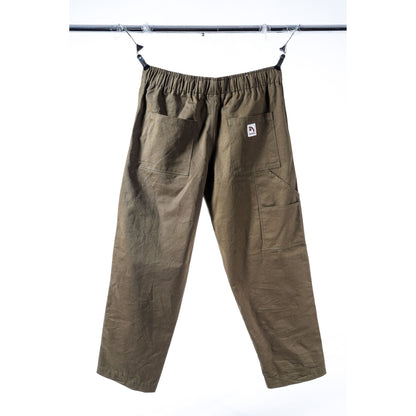 Olive green cargo baggy skate pants with an elastic waistband, hanging from a metal bar against a white background. Features a small white brand patch on the back pocket.
