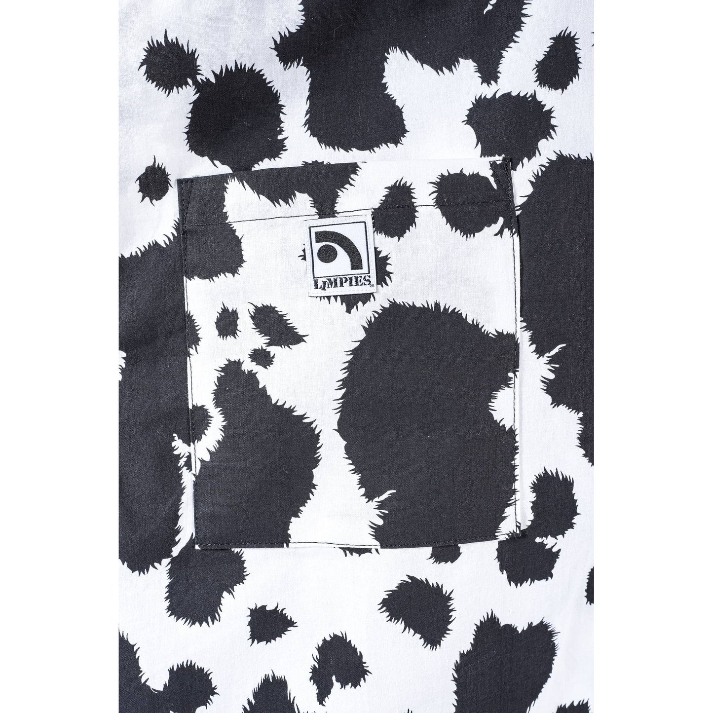 Close-up of a black and white cow print  Limpies baggy skate pants fabric with a front pocket featuring a visible Limpies Brand label.