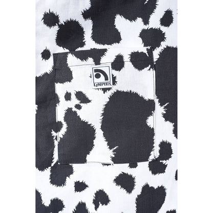 Close-up of a black and white cow print  Limpies baggy skate pants fabric with a front pocket featuring a visible Limpies Brand label.