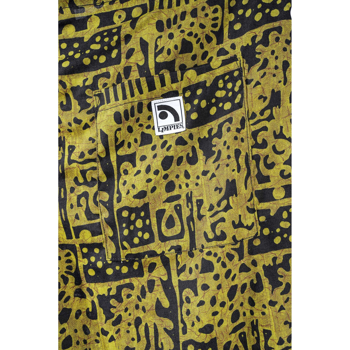 Close-up of a yellow and black patterned  Limpies baggy skate shorts, featuring a front pocket with a white square patch that reads 'Limpies'.