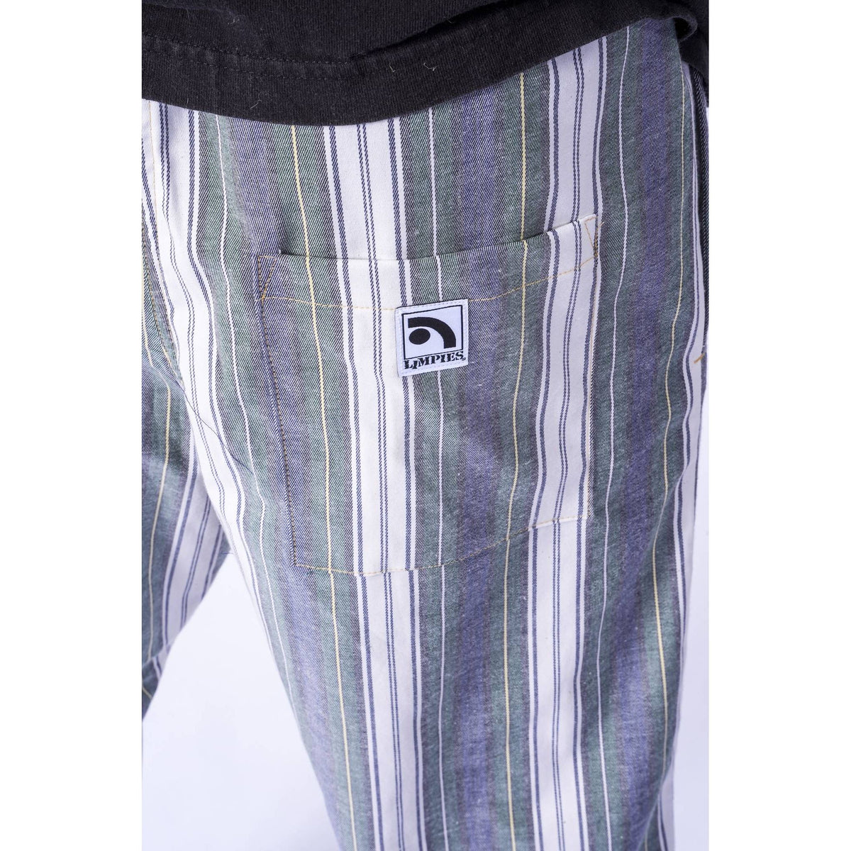 Close-up of striped pants with a front pocket featuring a visible Limpies logo patch, worn with a black top.