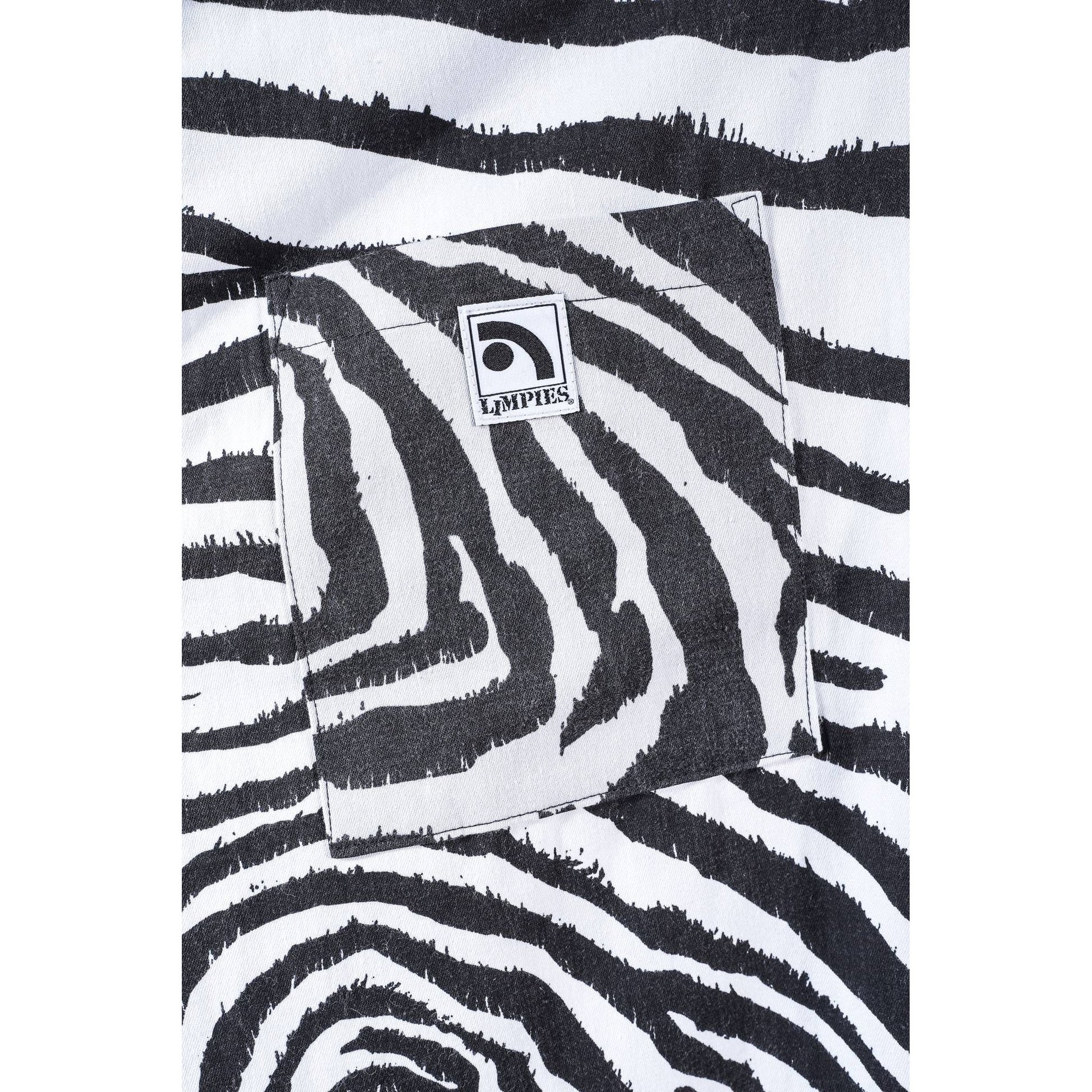 Close-up of a black and white zebra print baggy skate pants with a square pocket and a visible Limpies logo patch.
