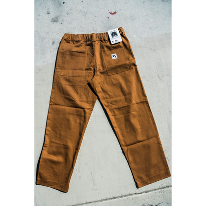 Brown baggy skate pants with a brand tag on a concrete surface