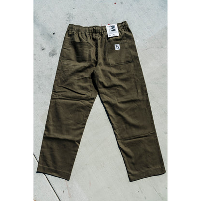 olive Green baggy skate pants with a brand tag on a gray concrete floor