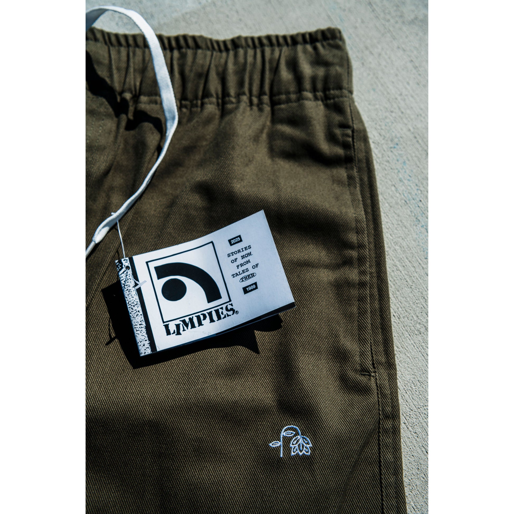 olive green baggy skate pants with a brand tag on a gray surface