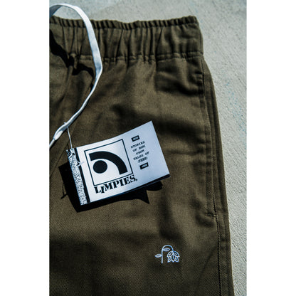 olive green baggy skate pants with a brand tag on a gray surface
