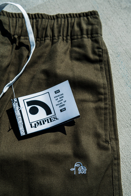 olive green baggy skate pants with a brand tag on a gray surface